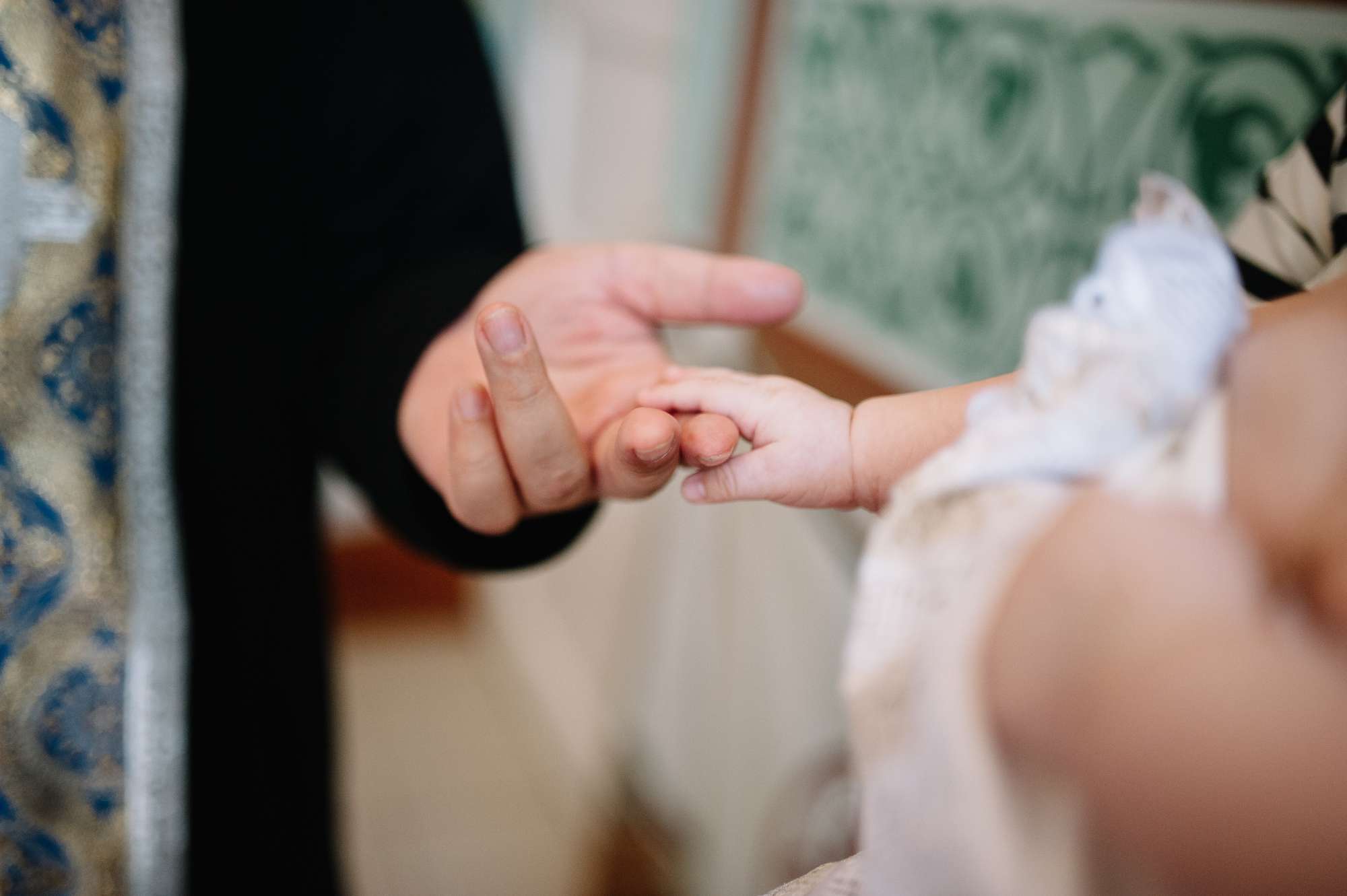 En person håller i en bebis hand.