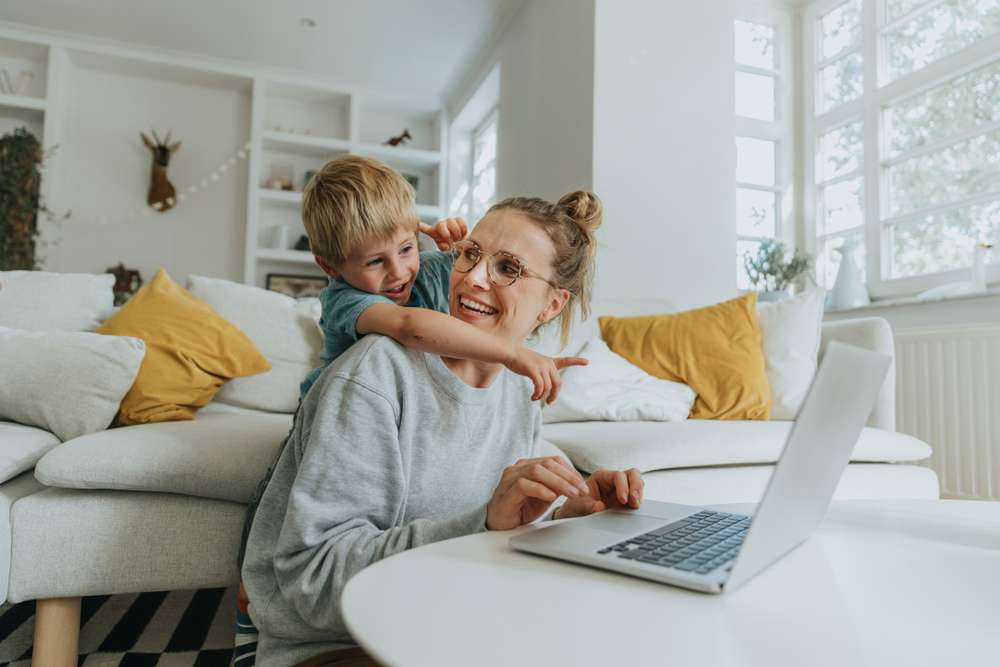 Mamma och ett barn sitter framför en laptop. Barnet pekar på skärmen.